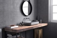 a grey Scandinavian bathroom with dark tiles on the floor, concrete walls, an industrial vanity, black fixtures