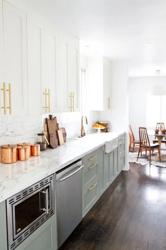 a light green and white mid-century modern kitchen with marble countertops and a backsplash plus gold touches