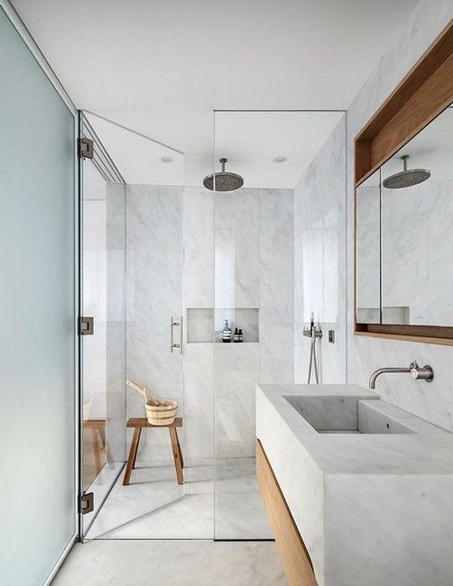 a light grey bathroom fully clad with grey large scale tiles, with touches of wood for warmth and much natural light