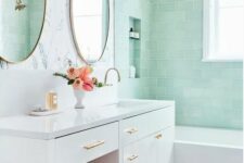a lovely bathroom with mint green tiles, a flower wall, geo tiles on the floor, a large vanity and a pink pouf