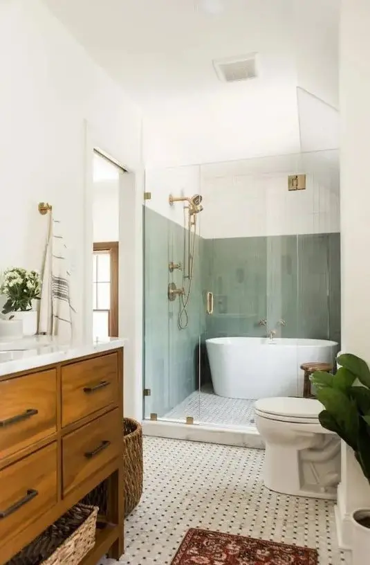 a mid century modern bathroom with sage green tiles in the bathing zone, a printed tile floor, a stained vanity and a basket