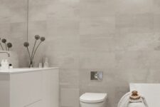 a minimalist greige bathroom clad with large format tiles, a tub clad with tiles, a sleek vanity
