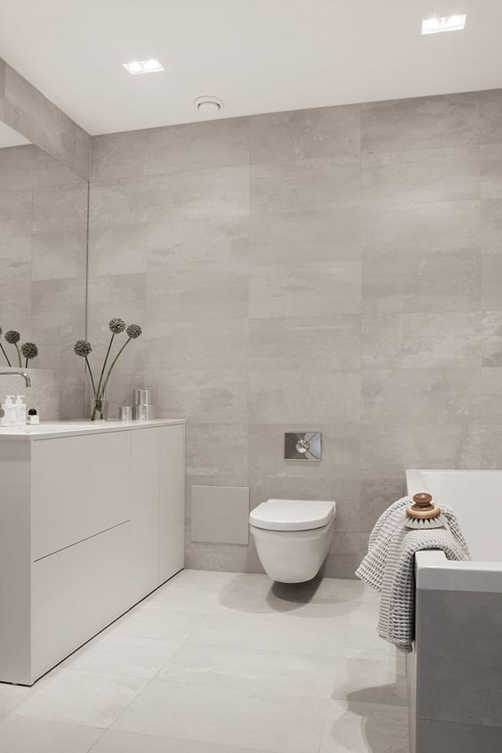 a minimalist greige bathroom clad with large format tiles, a tub clad with tiles, a sleek vanity