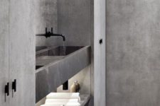 a minimalist grey bathroom done with marble, stone and concrete, with black fixtures and plenty of storage space