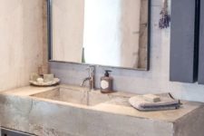 a minimalist industrial bathroom with concrete walls, a concrete and metal vanity, pendant lamps and a large mirror