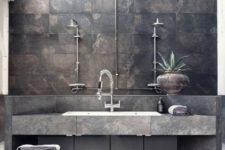 a minimalist industrial bathroom with dark stone tiles, a stone vanity, neutral fixtures and wooden furniture