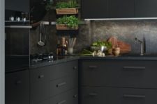a minimalist meets industrial black kitchen with metal cabinets, black stone countertops and a backsplash plus greenery