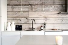 a minimalist white kitchen with sleek cabinets and a kitchen island and whitewashed wooden backsplash looks cozy and ethereal