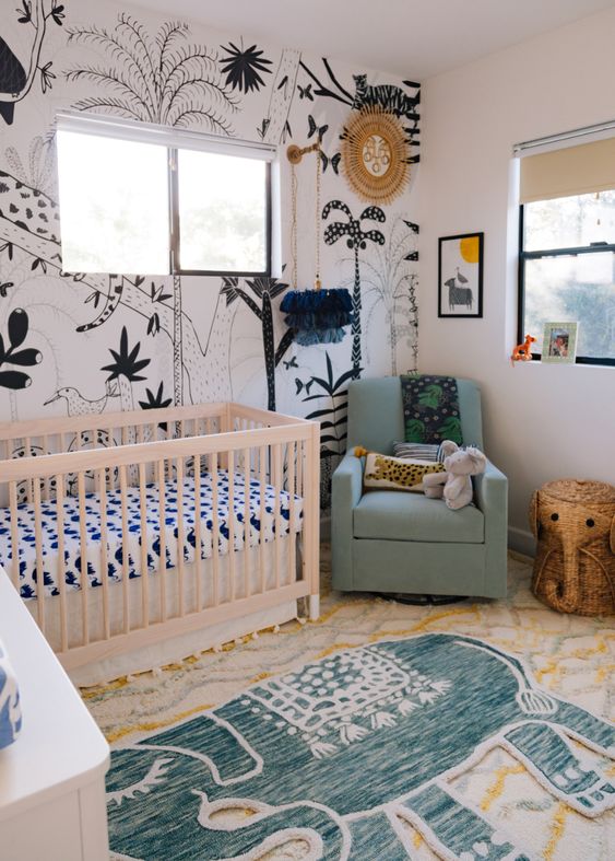 a modern boho jungle nursery with a statement black and white wall, layered rugs, animal toys and bright furniture