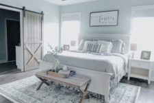 a modern farmhouse bedroom with white furniture, an upholstered bench, a vintage chandelier and ruffle bedding
