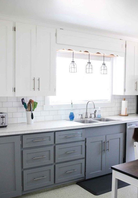 a modern farmhouse kitchen with upper white cabinets, lower grey ones, pendant lamps and metallic touches here and there