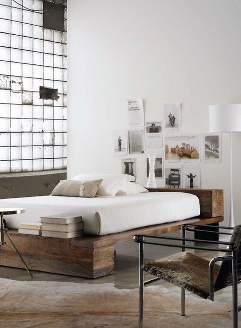 a modern industrial bedroom with a grid wall, a rough wood bed, a metal chair and faux animal skins and a metal chair