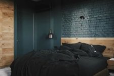 a modern industrial farmhouse bedroom with black brick walls, a neutrla wooden bed and wall and dark lamps