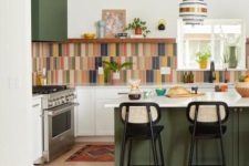 a modern kitchen with green adn white cabinetry, a colorful tile backsplahs, some decor and pendant lamps