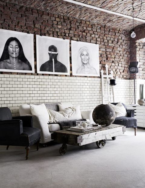 a modern meets industrial living room with brick walls, vintage and industrial furniture, a gallery wall and metal lamps