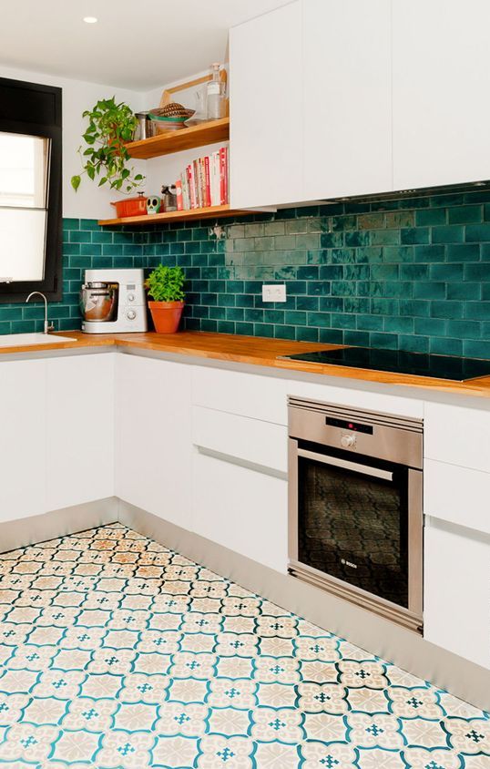 a modern white kitchen with sleek cabinets, butcherblock countertops, a bold green subway tile backsplash