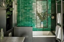 a moody bathroom with a statement emerald tile wall, a checked floor and a marble countertop looks super bold