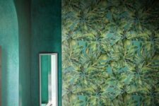 a moody tropical bathroom with a statement mural, a green plaster tub and green plaster walls