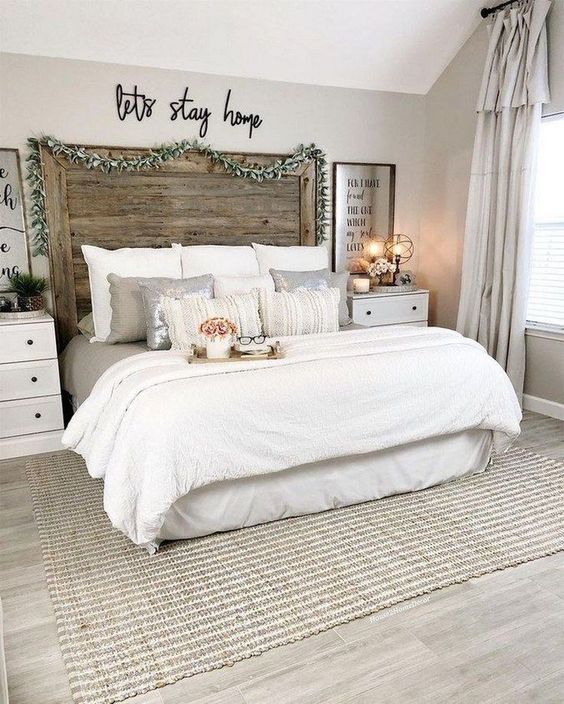 a neutral farmhouse space with an extended headboard, white furniture, some cozy bedding and a rug