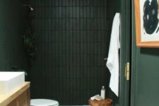 a refined and moody dark green and black bathroom with a white marble tile floor and a wooden vanity