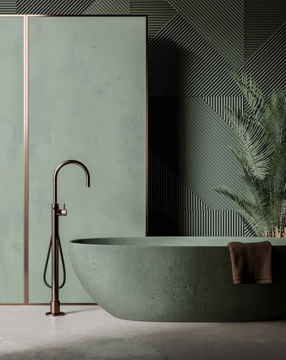 a refined green bathroom with a textural wall, a space divider and a green stone bathtub and some copper fixtures