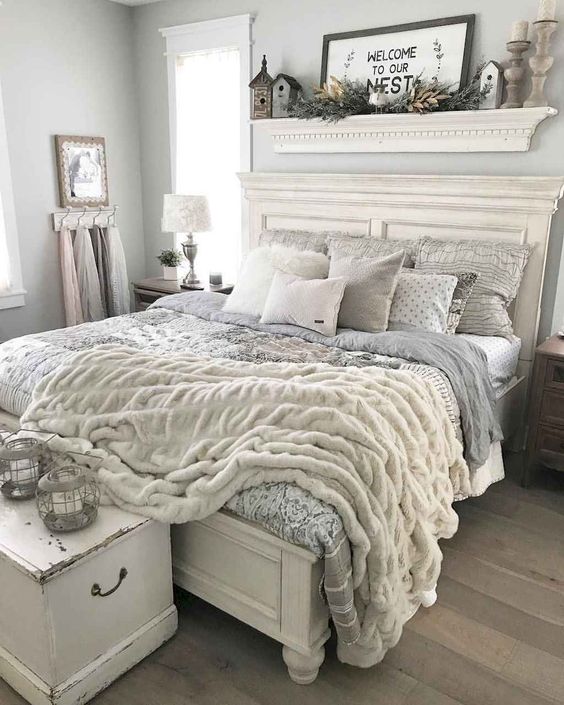 a romantic farmhouse bedroom in dove grey, with vintage white furniture, a shelf over the bed and catchy bedding plus a fur blanket