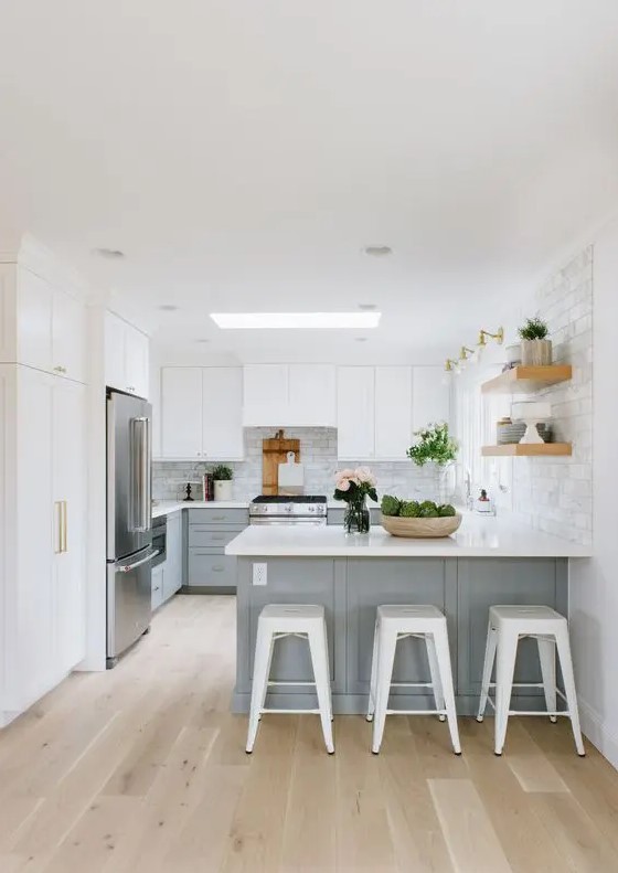 a serene kitchen with white upper cabinets and light grey lower ones, a large kitchen island, open shelves and white stools