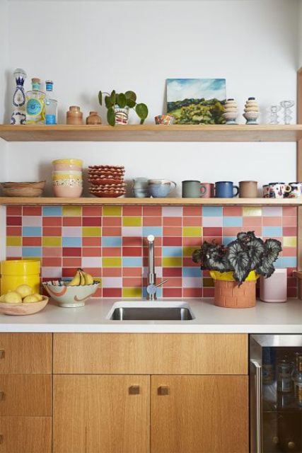 a stained kitchen with white countertops, a colorful tile backsplash and open shelves with colorful teaware