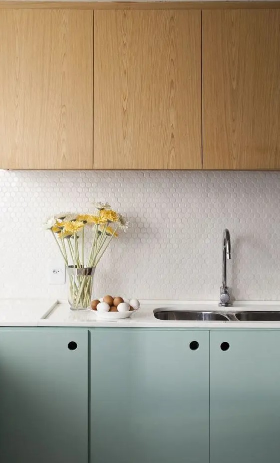 a stylish two-tone kitchen with stained and mint cabinets, a white penny tile backsplash and white countertops