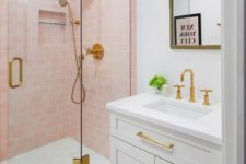 a sweet bathroom with light pink tiles in the shower, with white appliances and touches of gold to add elegance to the space