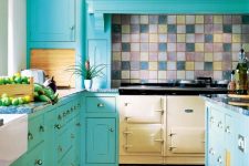 a turquoise kitchen with vintage cabinets, a vintage cooker and a colorful tile backsplash and black countertops