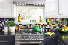 a two-tone kitchen in navy and white, with black countertops and a colorful tile backsplash is adorable and cool