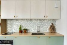 a two-tone kitchen with creamy and mint cabinets, butcherblock cabinets, a mosaic backsplash and butcherblock counterts