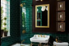 a vintage bathroom with emerald subway tiles, a free-standing sink, a mirror, a chandelier and some artwork