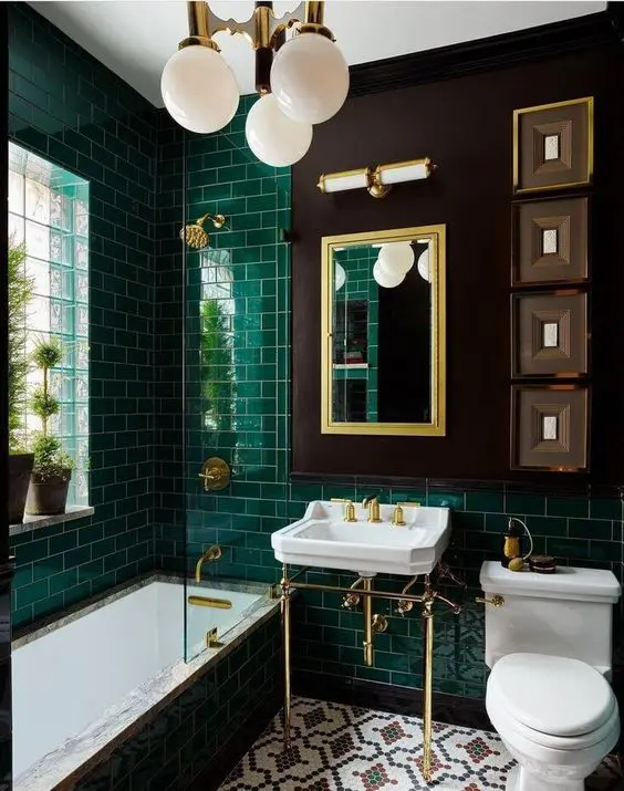 a vintage bathroom with emerald subway tiles, a free standing sink, a mirror, a chandelier and some artwork