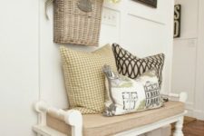 a vintage farmhouse entryway with racks with knobs, a vintage white bench with a burlap cushion and a rug