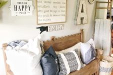 a vintage farmhouse entryway with wall lanterns, a carved wooden bench, lot sof pillows and some artworks on the wall