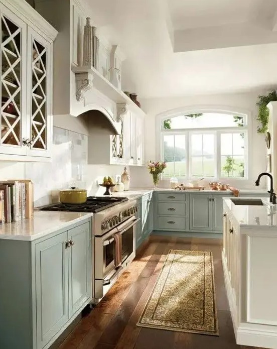 A vintage two tone kitchen with white and aqua colored cabinets, white stone countertops and a backsplash is a chic space