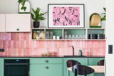 a whimsical kitchen with green cabinets and blush upper ones, a bold pink stacked tile backsplash and touches of black