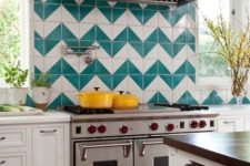 a white farmhouse kitchen with an extra bold chevron turquoise and white backsplash and stainless steel appliances