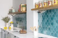 a white farmhouse kitchen with only lower cabinets and a blue fish scale tile backsplash plus white countertops