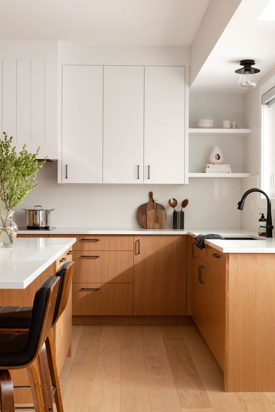 An elegant mid century modern kitchen with white and stained cabinets, a matching kitchen island and black stools