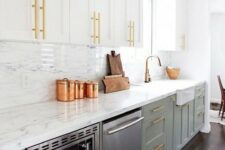 an exquisite two tone kitchen with white and sage green cabinets, a white quartz backsplash and countertops plus touches of gold
