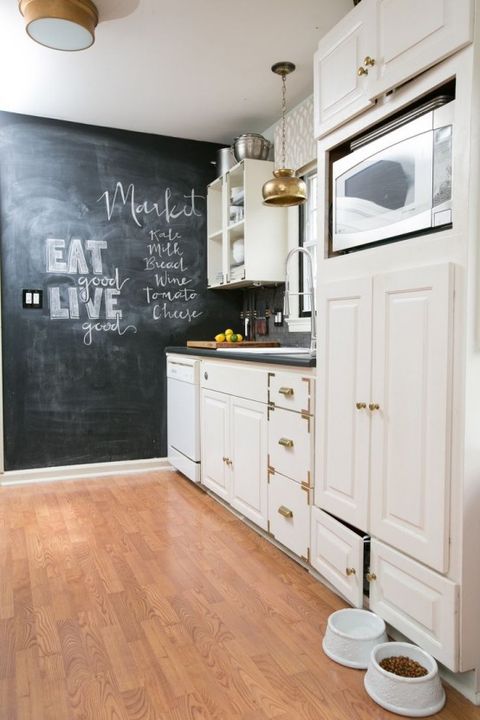 a white farmhouse kitchen with gold or brass touches, a chalkboard wall for marks and a grey tile backsplash