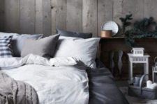a Nordic chalet bedroom with a reclaimed wood wall, grey and white bedding, candle lanterns and antlers on the wall