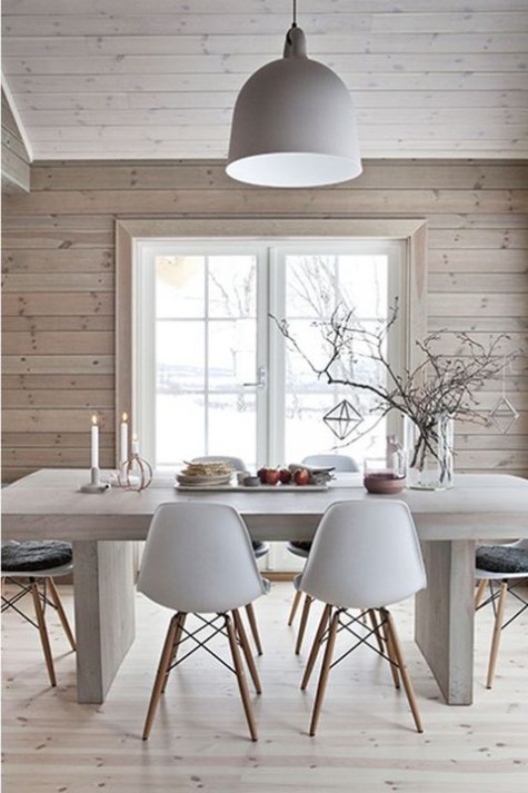 a Nordic chalet dining room done with whitewashed wood, with a white lamp and chairs plus some candles