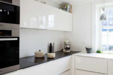 a black and white minimalist kitchen with sleek and shiny cabinets, pendant lamps and built-in appliances