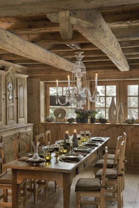 a chalet dining space all done with wood, with vintage carved furniture, a crystal chandelier and some candles