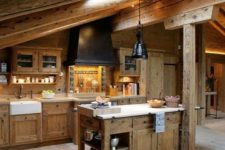 a chalet kitchen with wooden beams and a skylight, a wooden kitchen island and cabines, a black hood and lamps