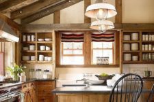 a chic chalet kitchen with wooden beams, wooden cabients and a kitchen island, stone countertops and pendant lamps